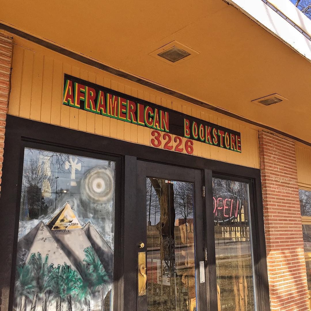 Front door displays vibrant mural of pyramids beneath bookstore sign. "AFRAMERICAN BOOKSTORE 3226" appears above, with "OPEN" sign on glass.