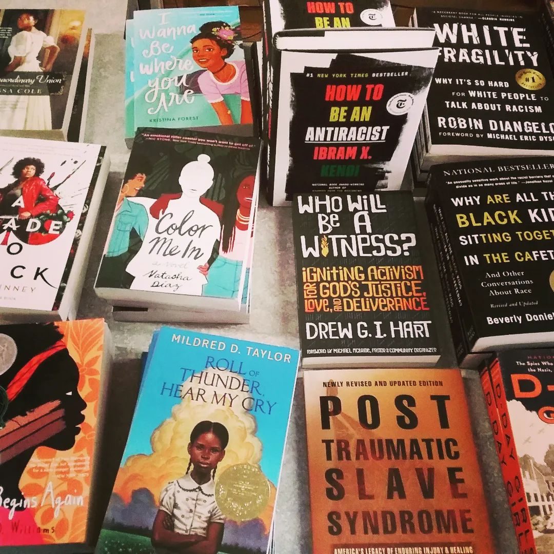 Books are neatly arranged on a display table, featuring diverse covers and titles about race, identity, activism, and personal stories.