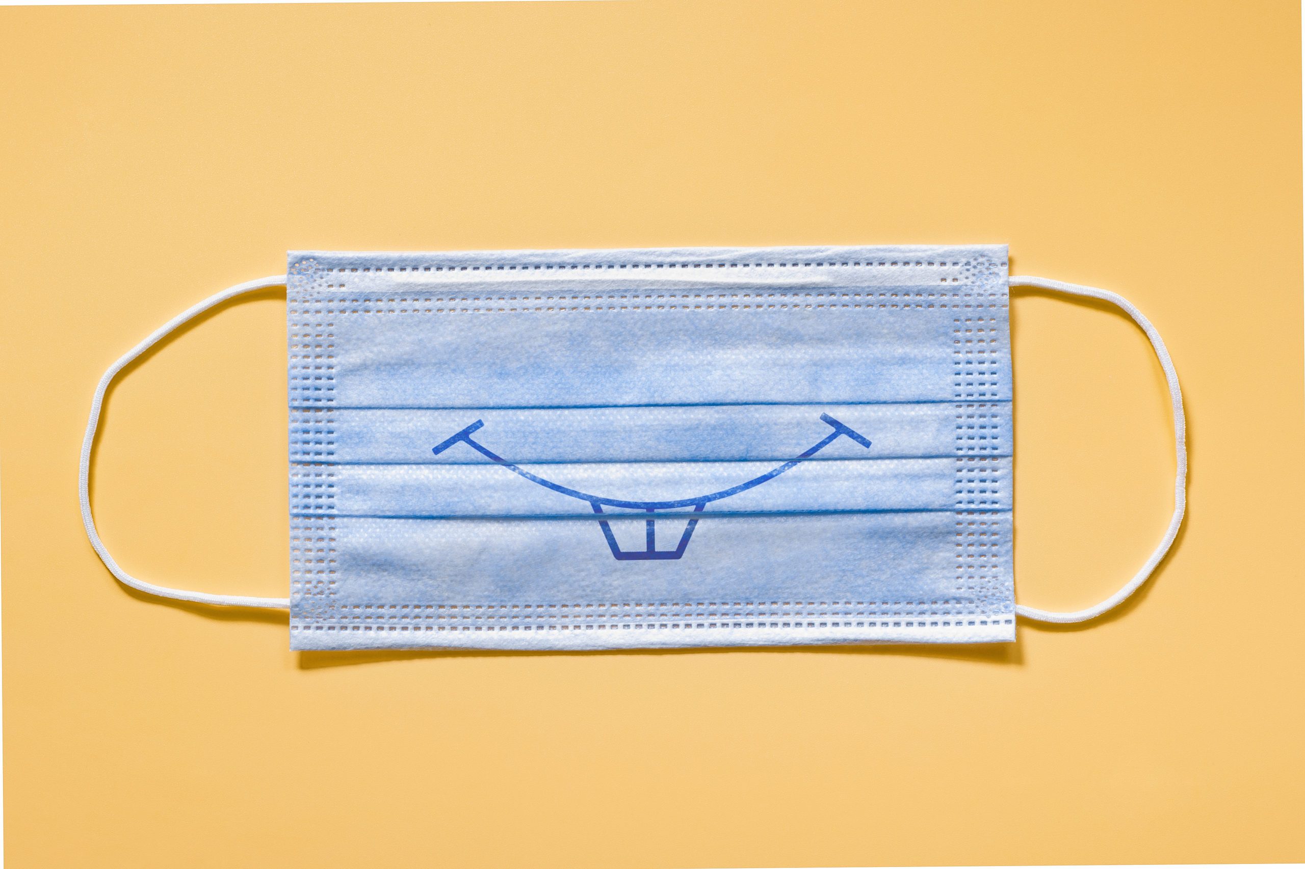 Medical protective face mask smiling on yellow background