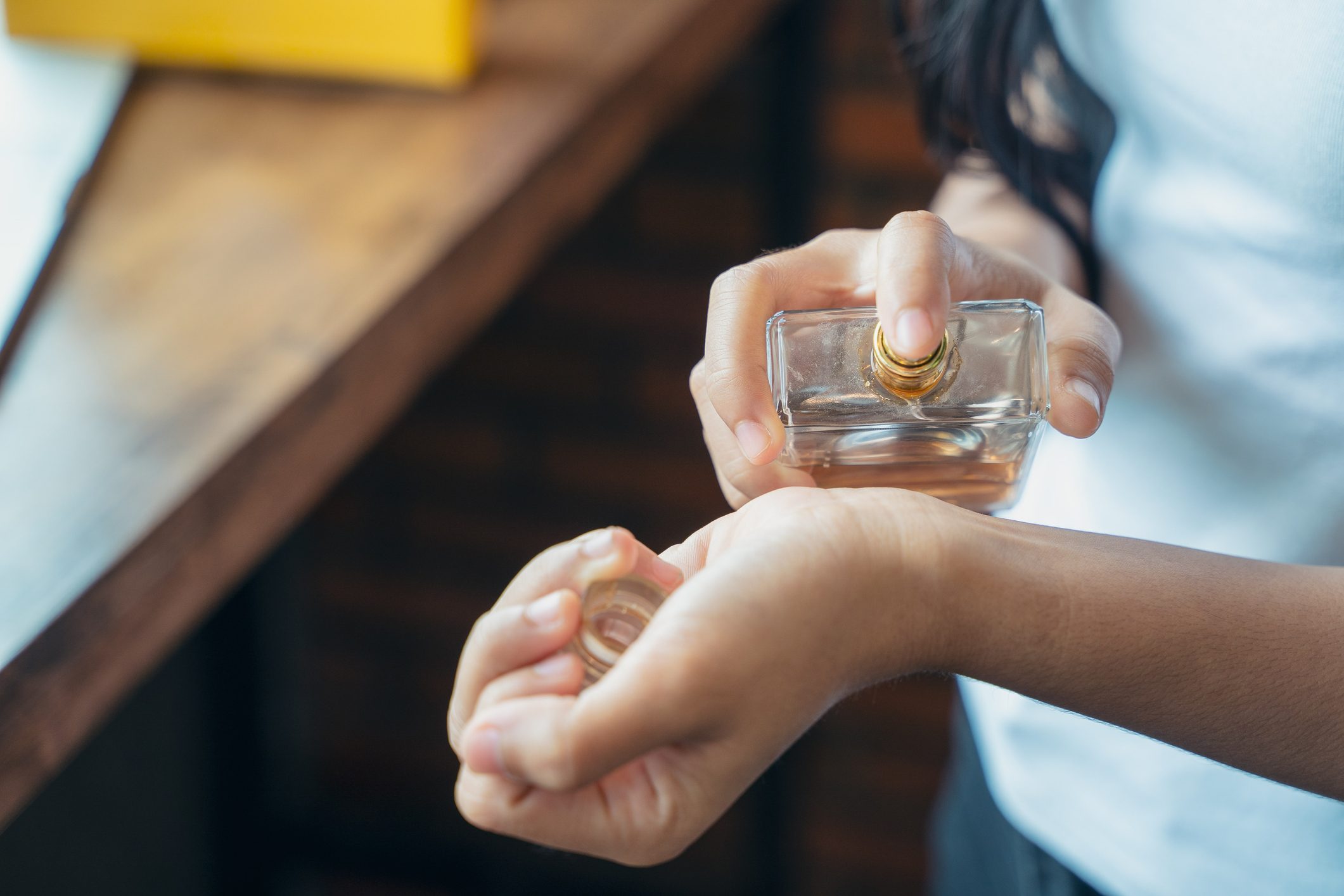 Beautiful young woman with bottle of perfume at home.