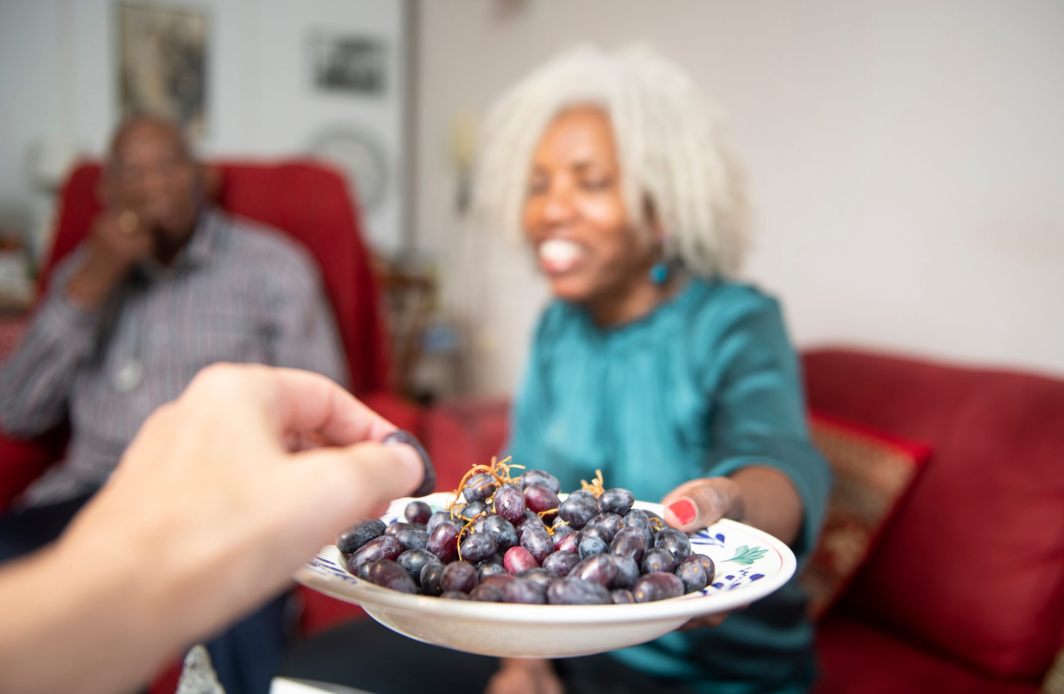 Personal view of a guest being offered grapes by a kind and beautiful senior woman