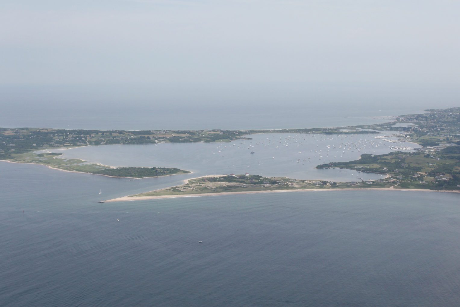 Coastline extends across the horizon, dotted with small islands and boats, under a clear sky and surrounded by calm ocean waters.