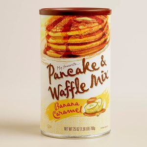 A cylindrical container displays a stack of pancakes with syrup. It features text: 