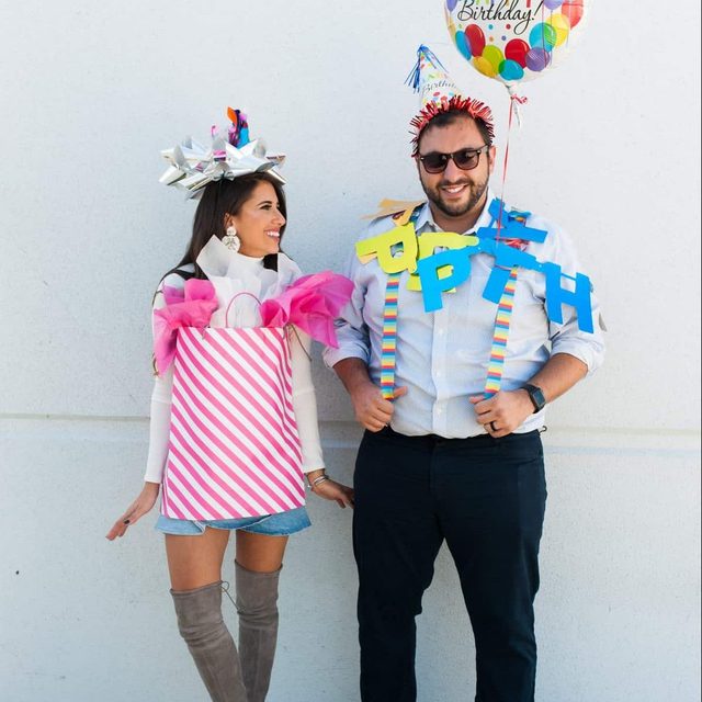People smiling, wearing gift-themed costumes; one holds a 