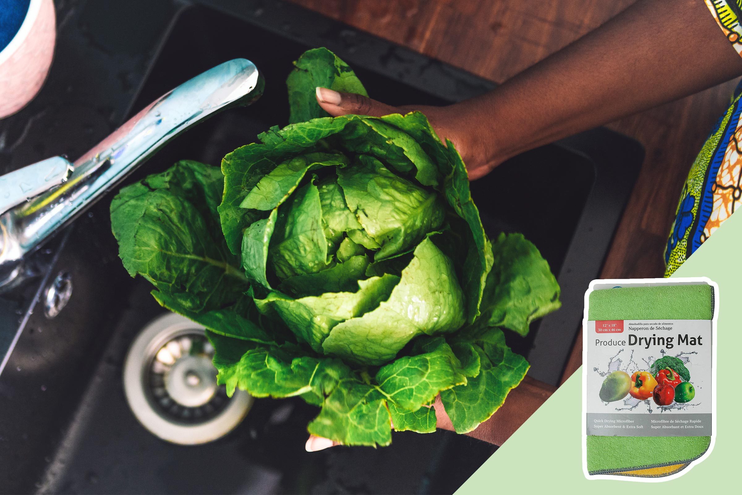 Lettuce held in hands, being washed in a kitchen sink; drying mat packaging displayed nearby on a wooden counter.