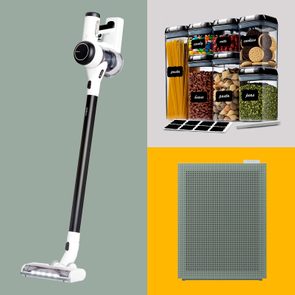 Vacuum cleaner stands upright, next to labeled food storage containers, positioned beside a yellow background with a perforated gray grid.