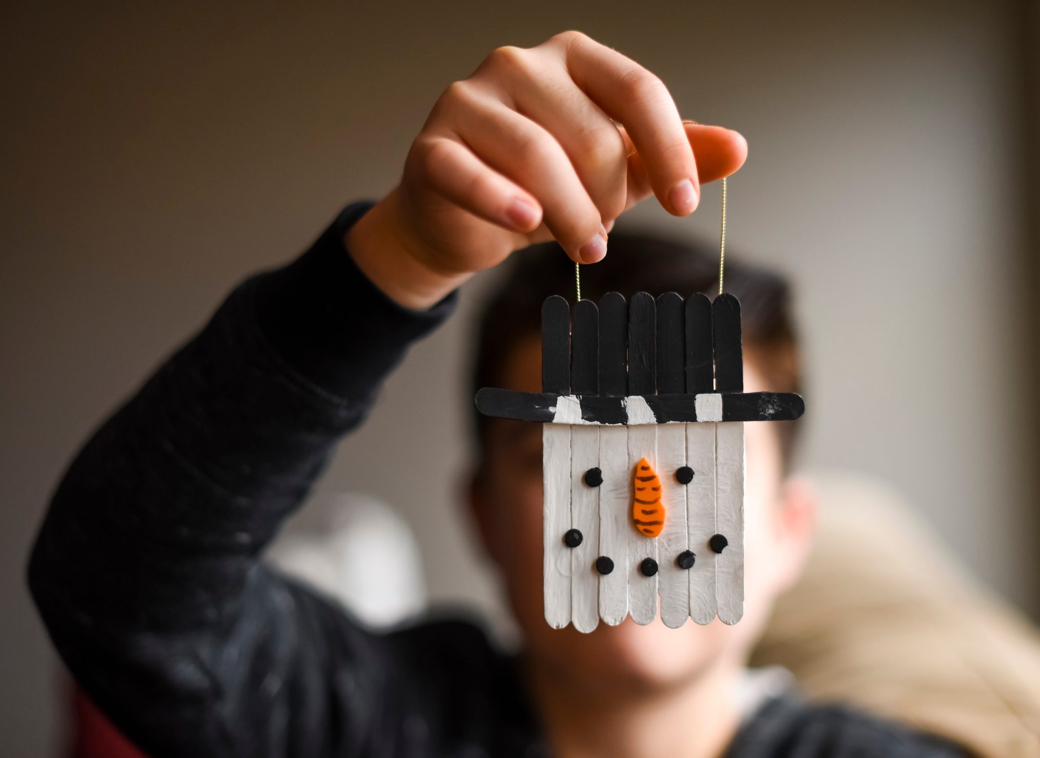 Close up of homemade snowman decoaration held by older boy.