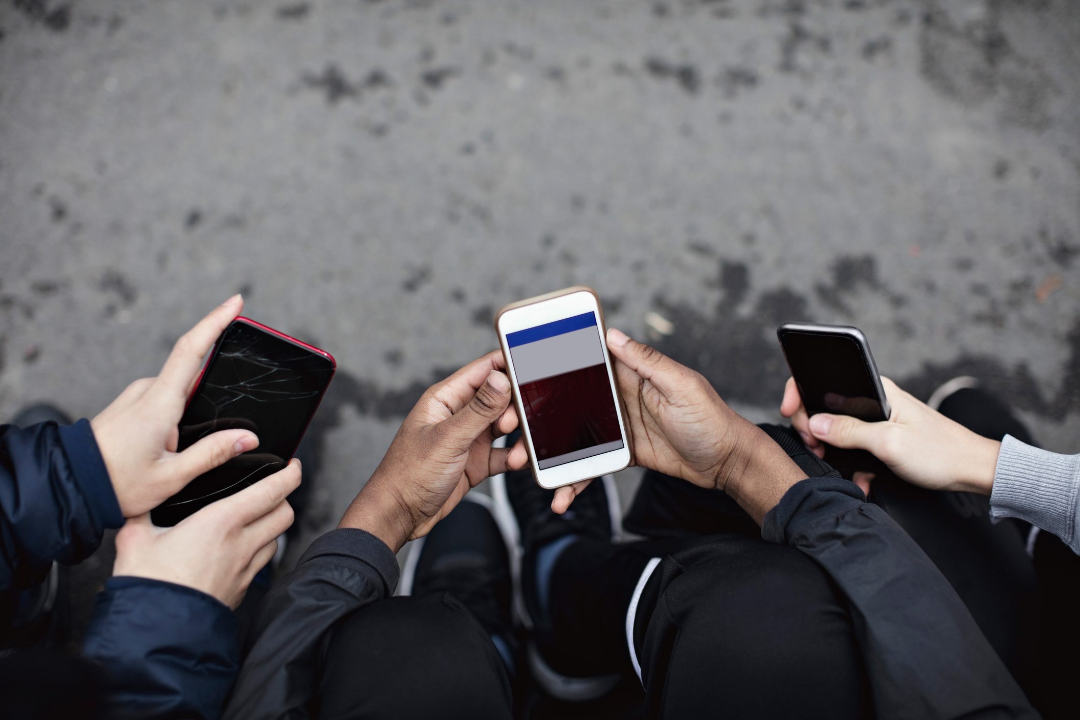 High angle view of friends using social media in mobile phone on street