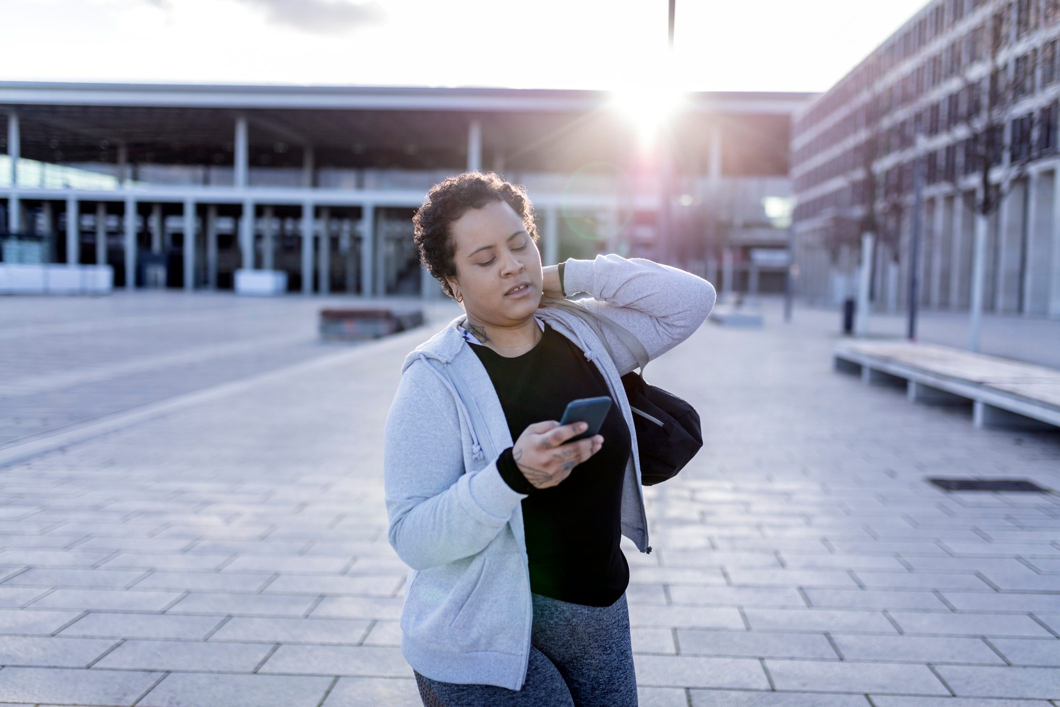 portrait of a young and curvy women with sports bag and mobile phone walking to her fitness club