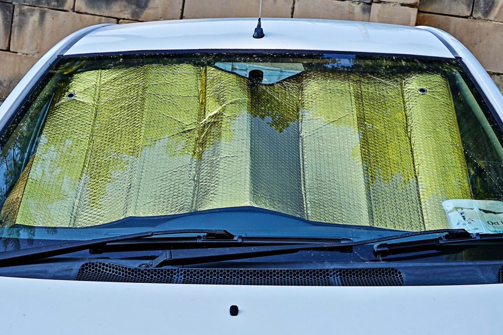 Windshield of car with protective reflective sunscreen surface inside car
