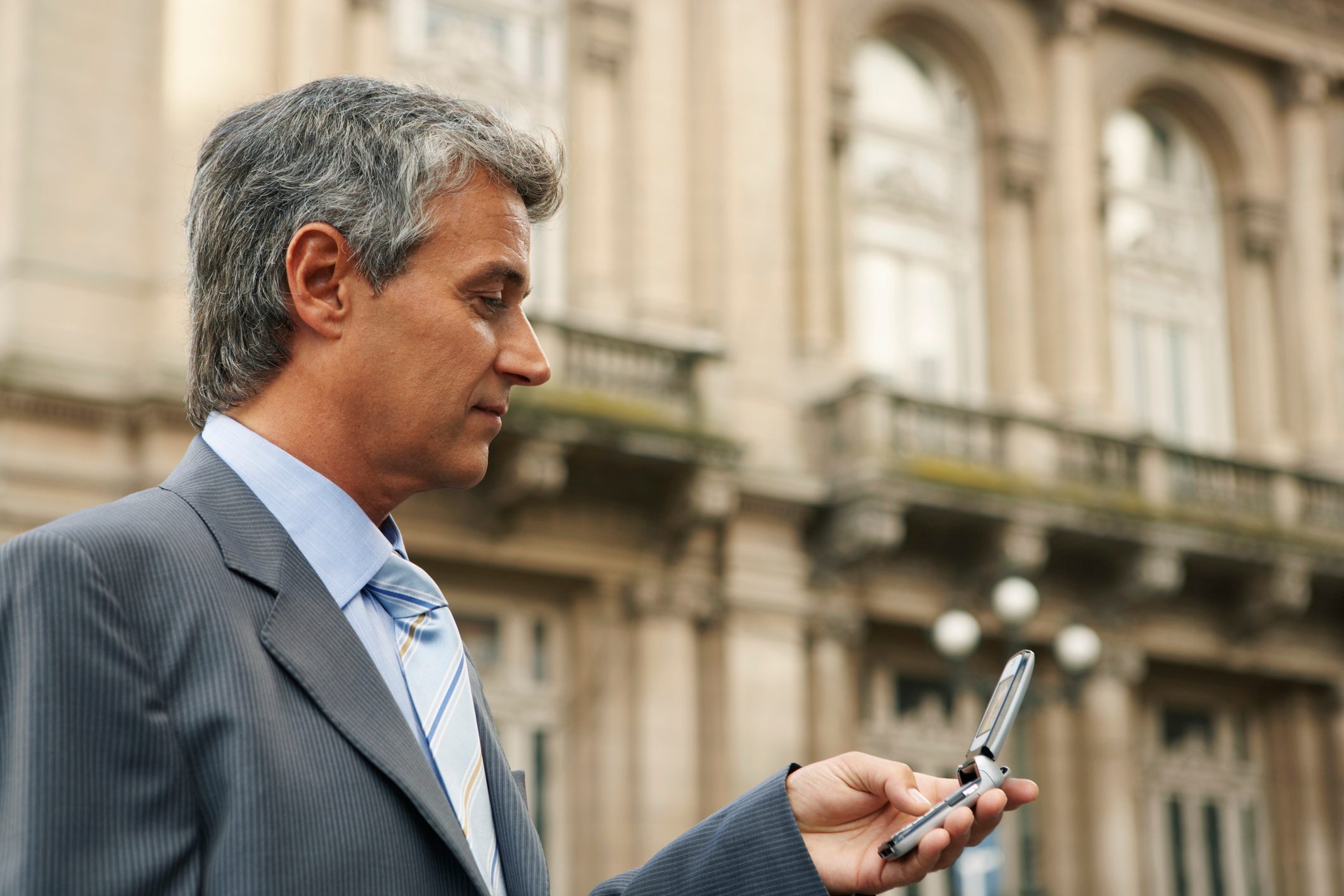 Mature businessman using mobile phone, close up, side view