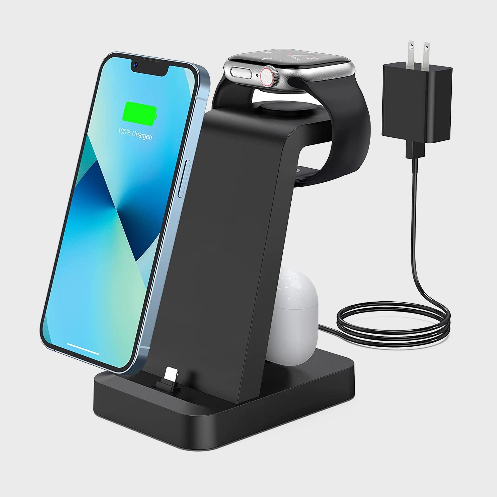 Charging stand holds smartphone, smartwatch, and earbuds, connected to a plug by a coiled cable. Smartphone screen shows "100% Charged" text.