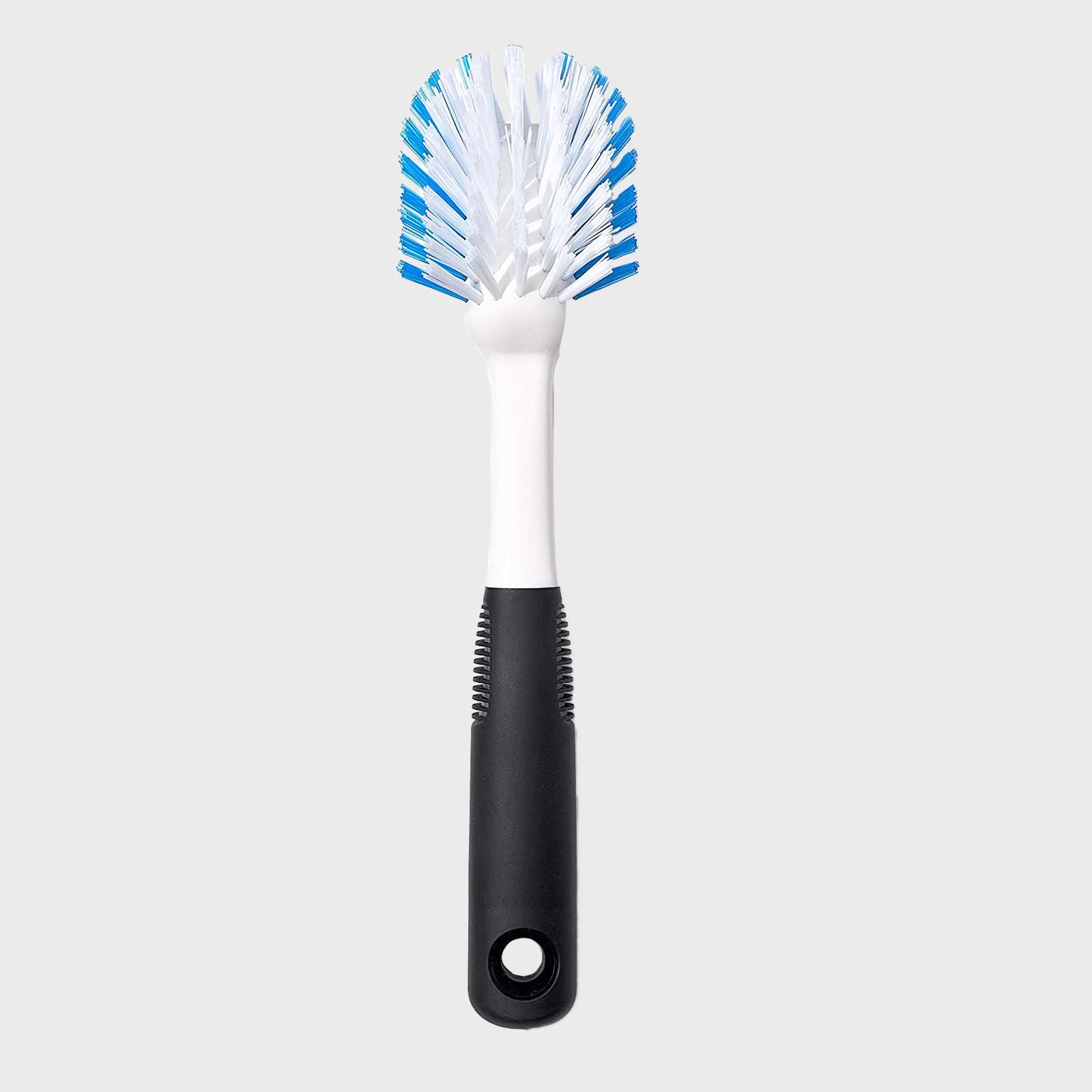 Brush with white and blue bristles stands vertically; black handle with grip texture, gray background.