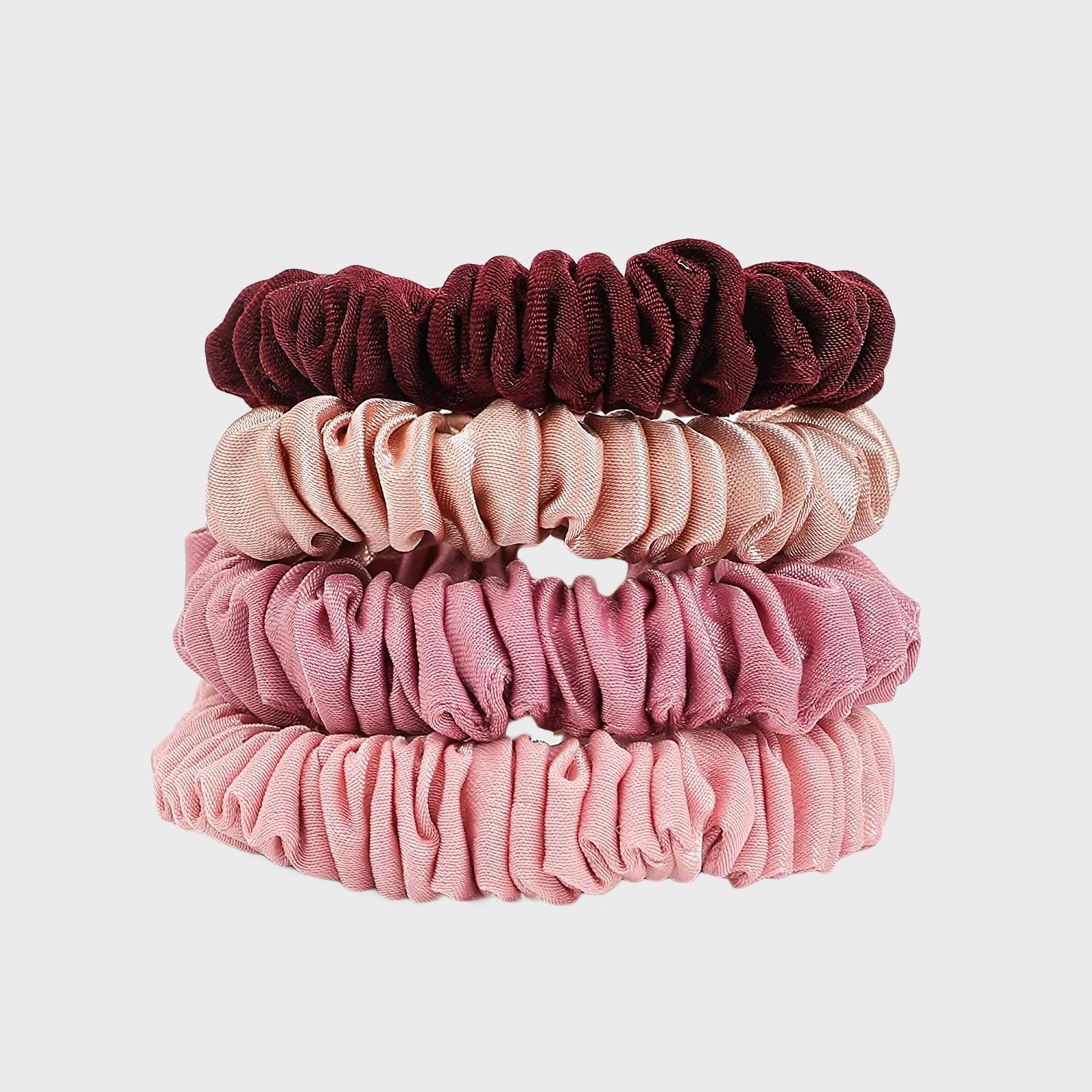 Three stacked, elasticated, fabric hair scrunchies showcased in varying shades of pink and maroon, against a plain white background.
