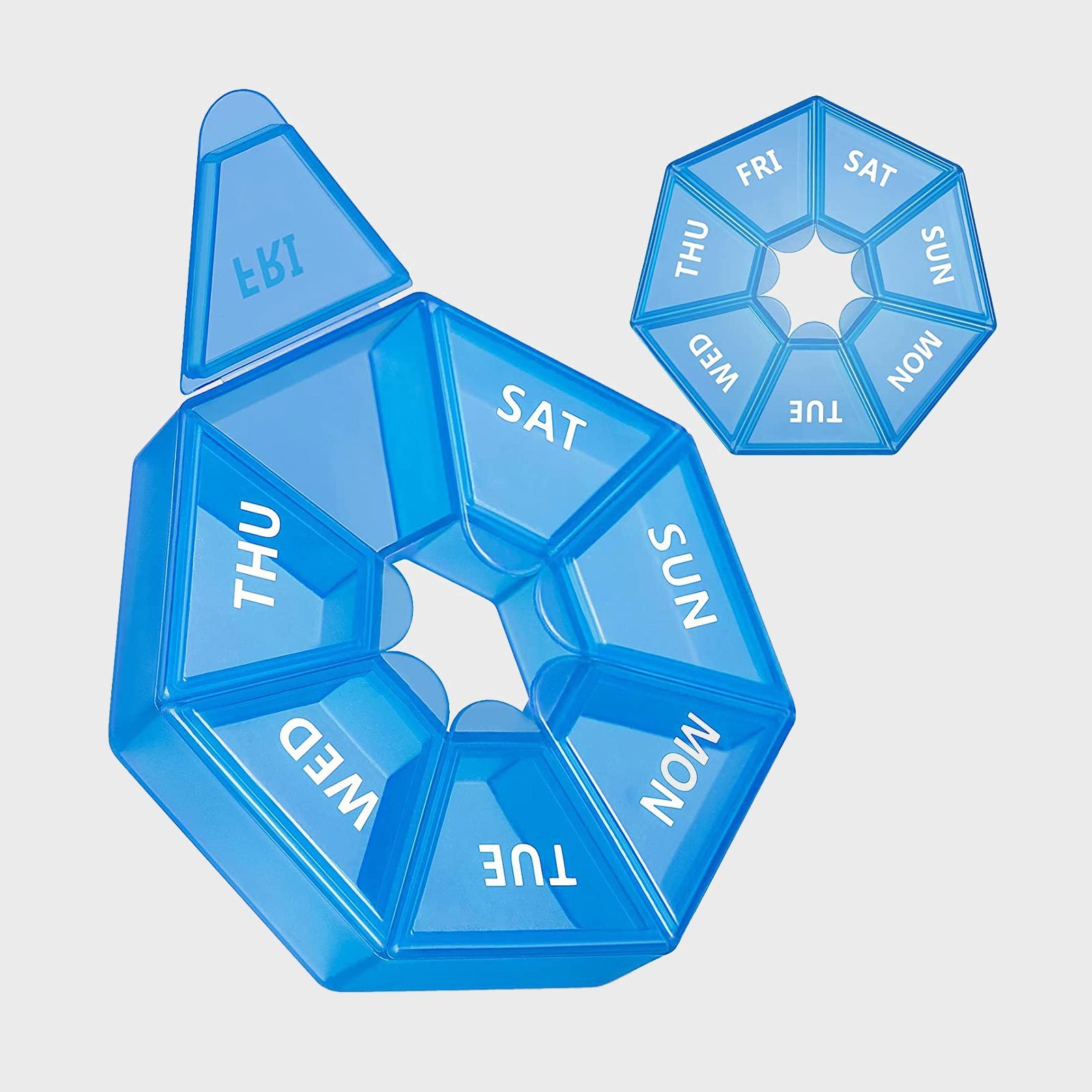 Blue, segmented pill organizer displaying days of the week, lying on a flat surface. Some compartments are open, others closed.