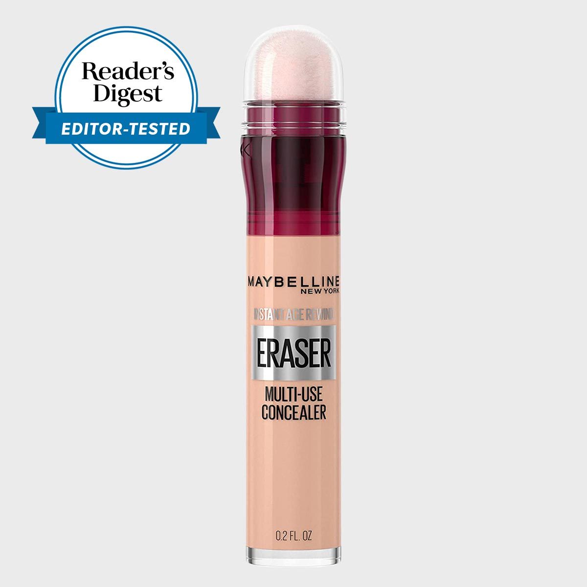 Concealer stick labeled "Maybelline Instant Age Rewind Eraser," capped with sponge applicator, sits against a plain background. Reader's Digest "Editor-Tested" badge visible.