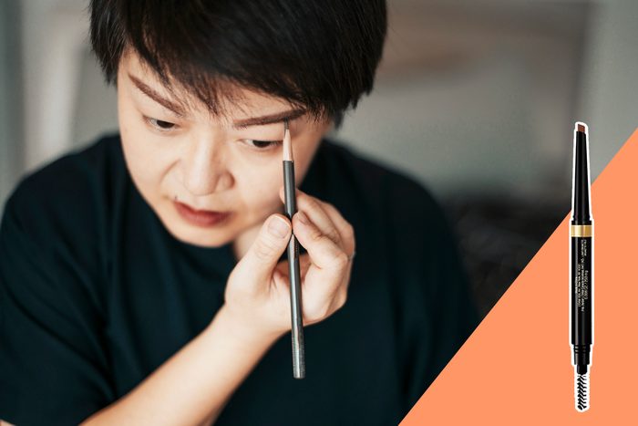 Person applying eyebrow pencil while looking in mirror; a makeup pencil shown separately with text: 
