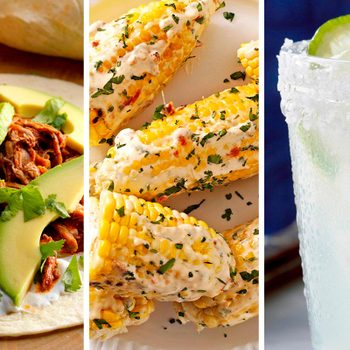 Taco with avocado and cilantro rests on tortilla; elote covered in creamy sauce lies on plate; margarita in sugar-rimmed glass with lime slice.