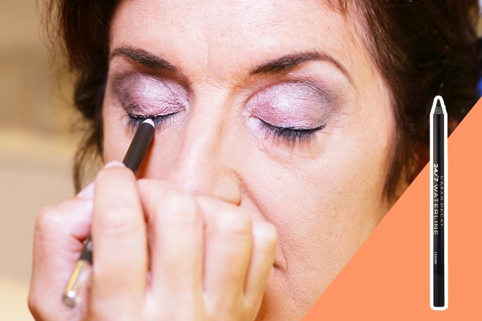 Person applying eyeliner on eyelid; eyes closed, makeup being applied carefully. Right side features eyeliner product labeled 
