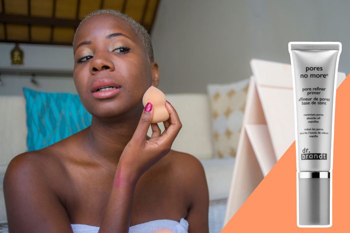 A person applies makeup sponge to face in a cozy room; 