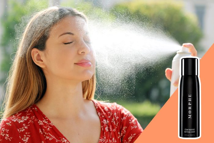 A woman sprays her face with mist outdoors; 