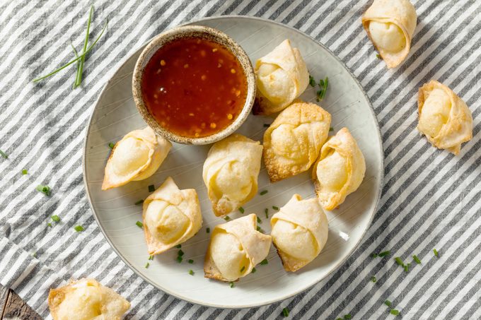 crab ragoons on a plate with a small bowl of dipping sauce in the middle of the plate