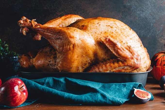 Roasted whole turkey on a table with apple, pumpkin and figs for family Thanksgiving Holiday.