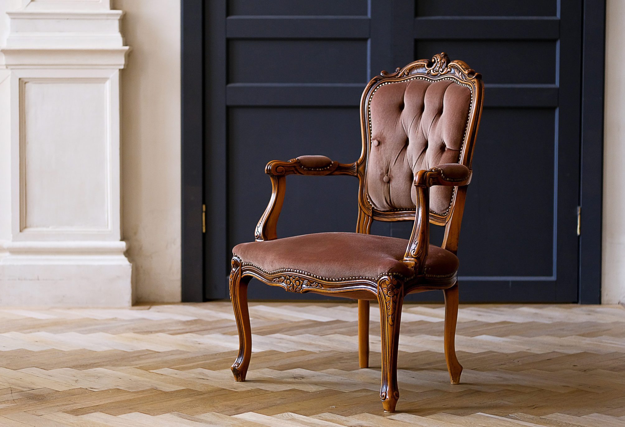Beige velour chair against the black doors in the living room. The interior of the room in retro style.