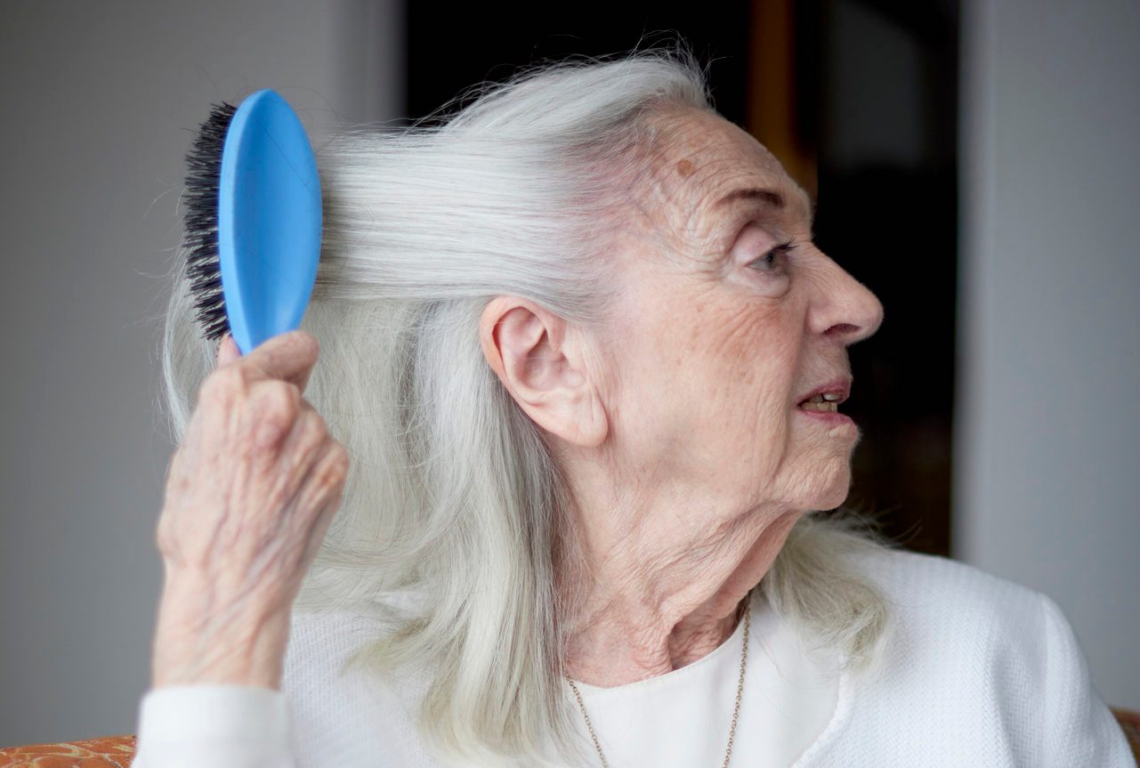 Older Caucasian woman brushing hair