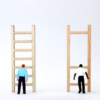 Two miniature figures stand before ladders; one has evenly spaced rungs, the other has widely spaced rungs, against a plain white background.