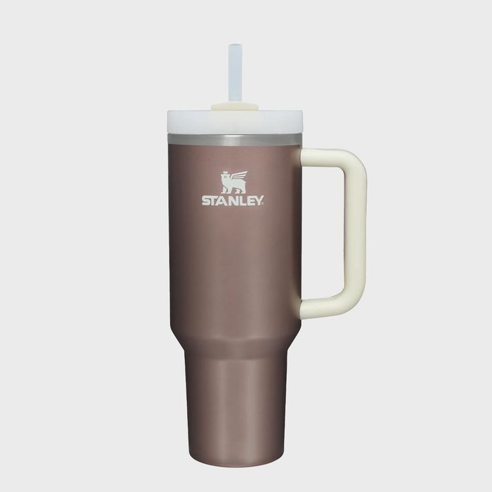 A brown insulated tumbler with a white straw rests on a plain background; labeled 