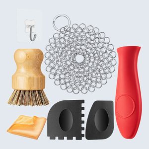 Various kitchen tools displayed; includes a wooden brush, chain scrubber, red handle, adhesive hook, cloth, and black plastic scrapers on light background.