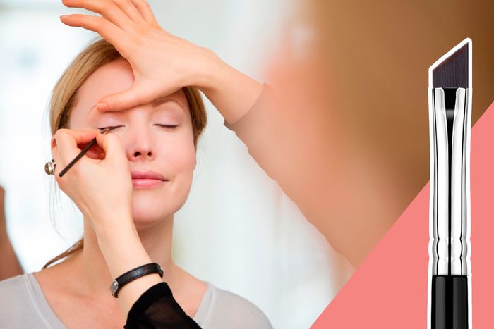 A makeup artist applies eyeliner to a woman's closed eyes, with a close-up of an angled brush on the right.