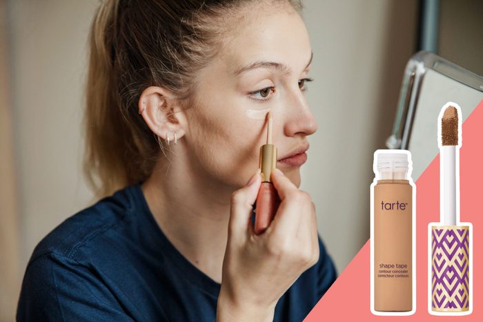 Person applying concealer under eye, sitting at a mirror. Makeup product and applicator displayed on a split colored background. Text: 