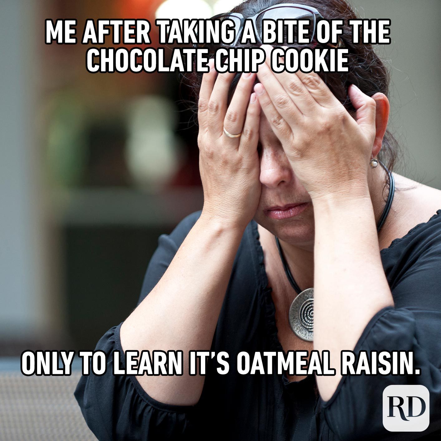 Woman rubbing her eyes with hands. Meme text: Me after taking a bite of the chocolate chip cookie only to learn it’s oatmeal raisin.