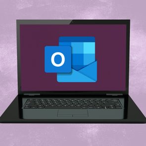 Laptop displays Microsoft Outlook icon, surrounded by a plain purple background.