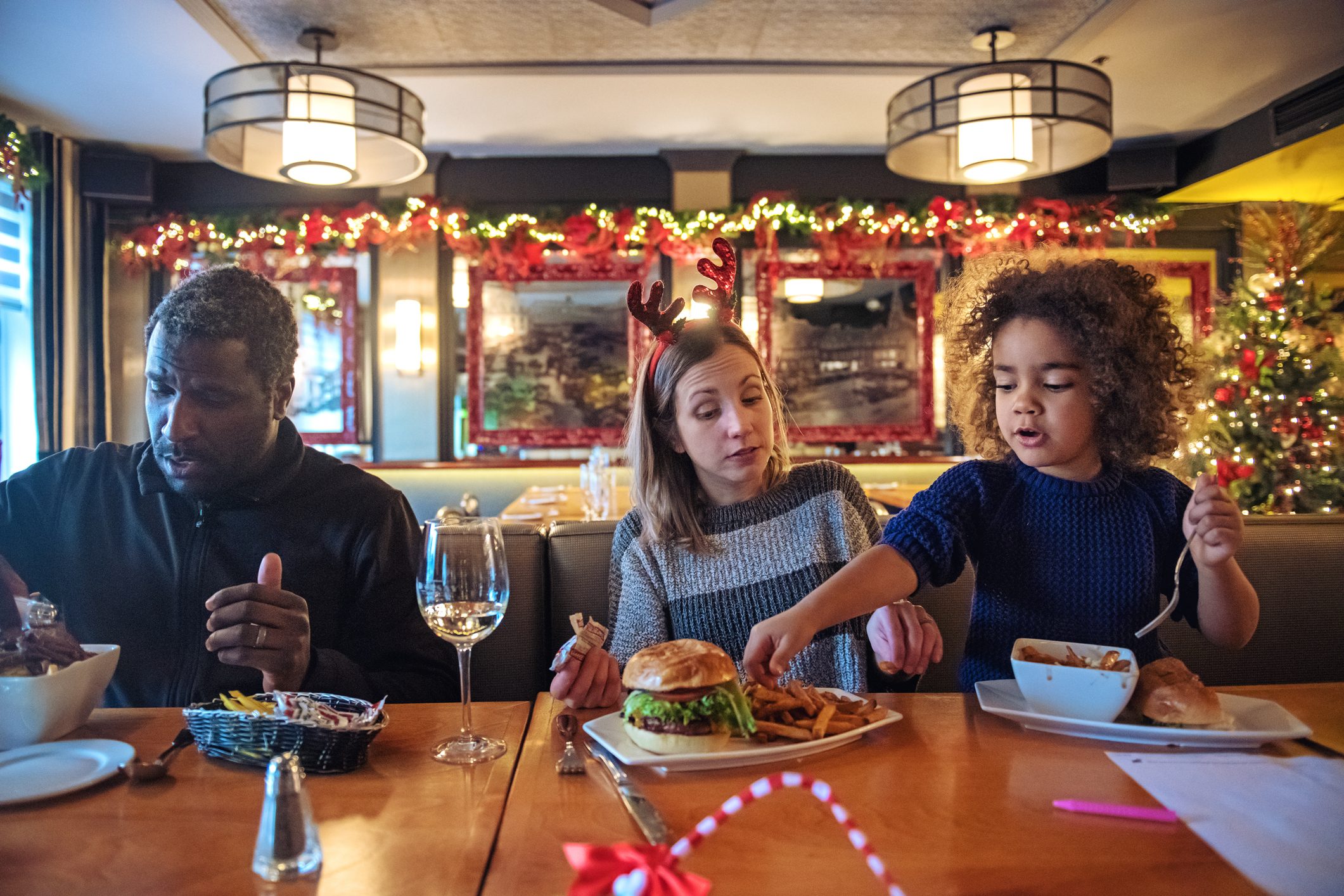 Multi-ethnic family shopping for Christmas, having a break in a restaurant