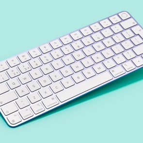 A white keyboard rests diagonally on a light blue background, showcasing its compact design and clean layout.