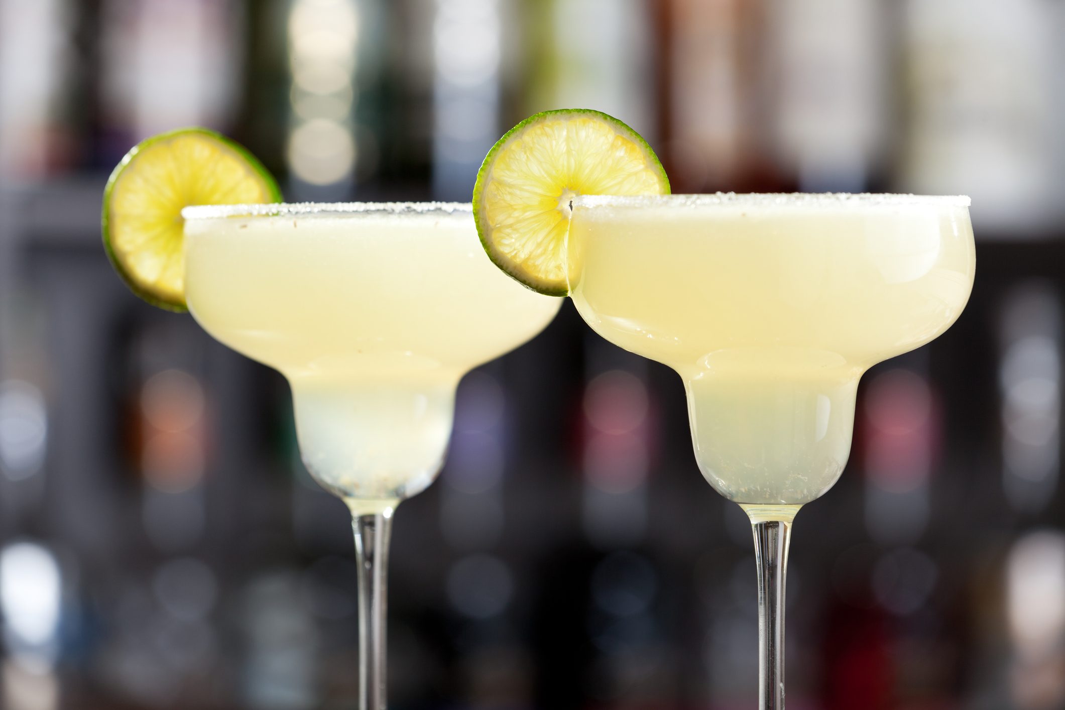 Two margaritas with lime wedges and salted glasses