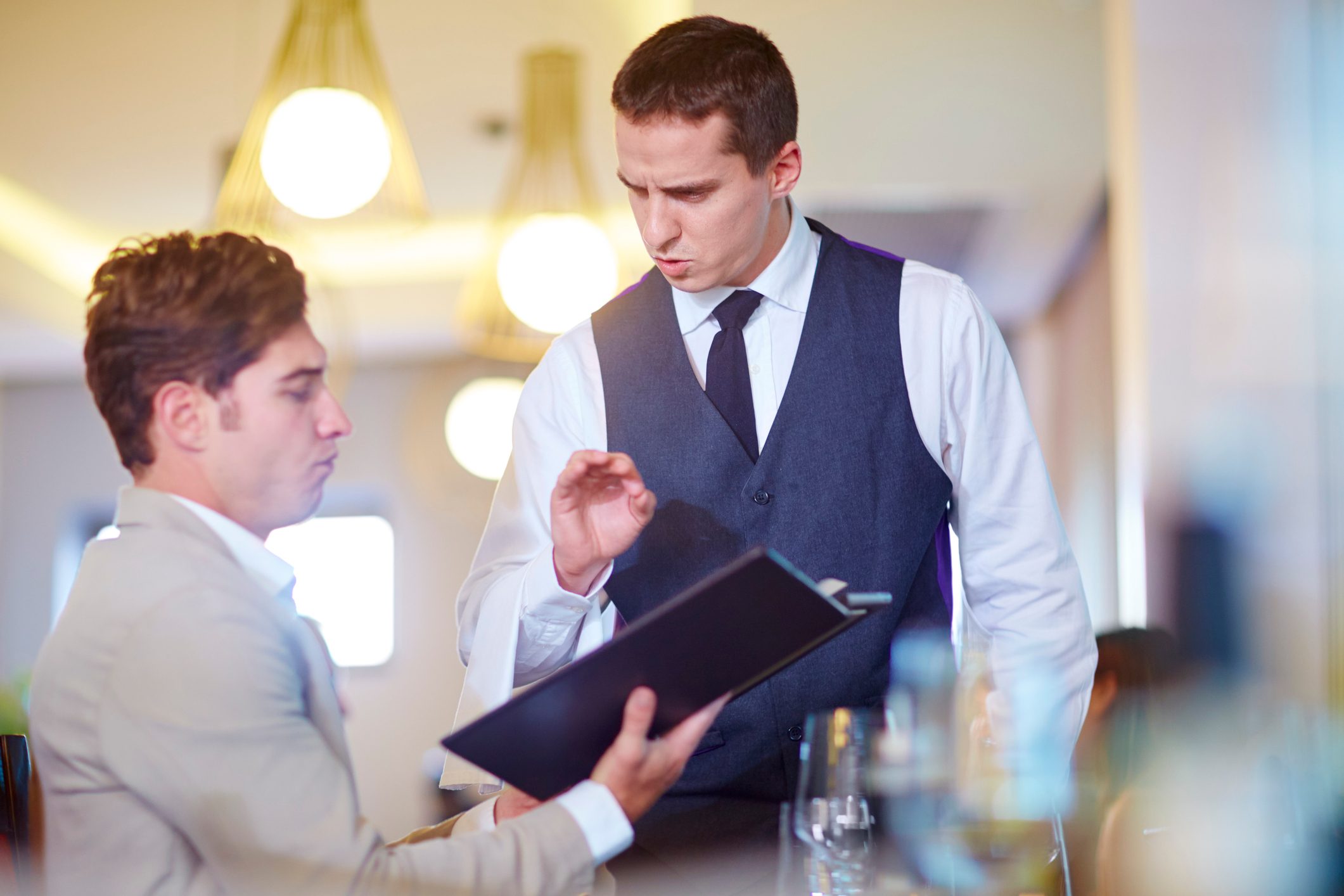 Businessman placing an order with waiter at hotel restaurant