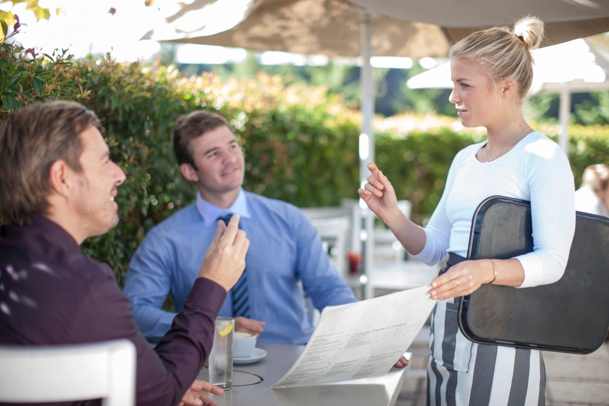 Waitress talking to two businessmen at outside restaurant