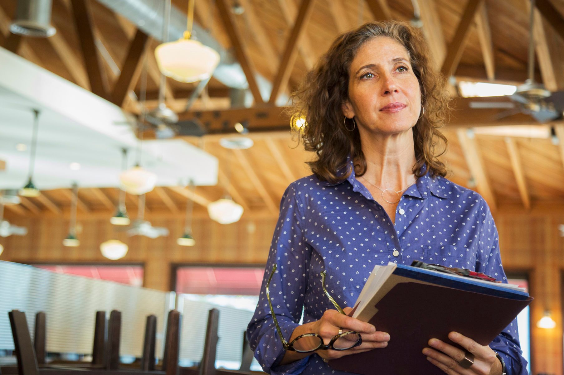 Pensive Caucasian woman holding paperwork in restaurant