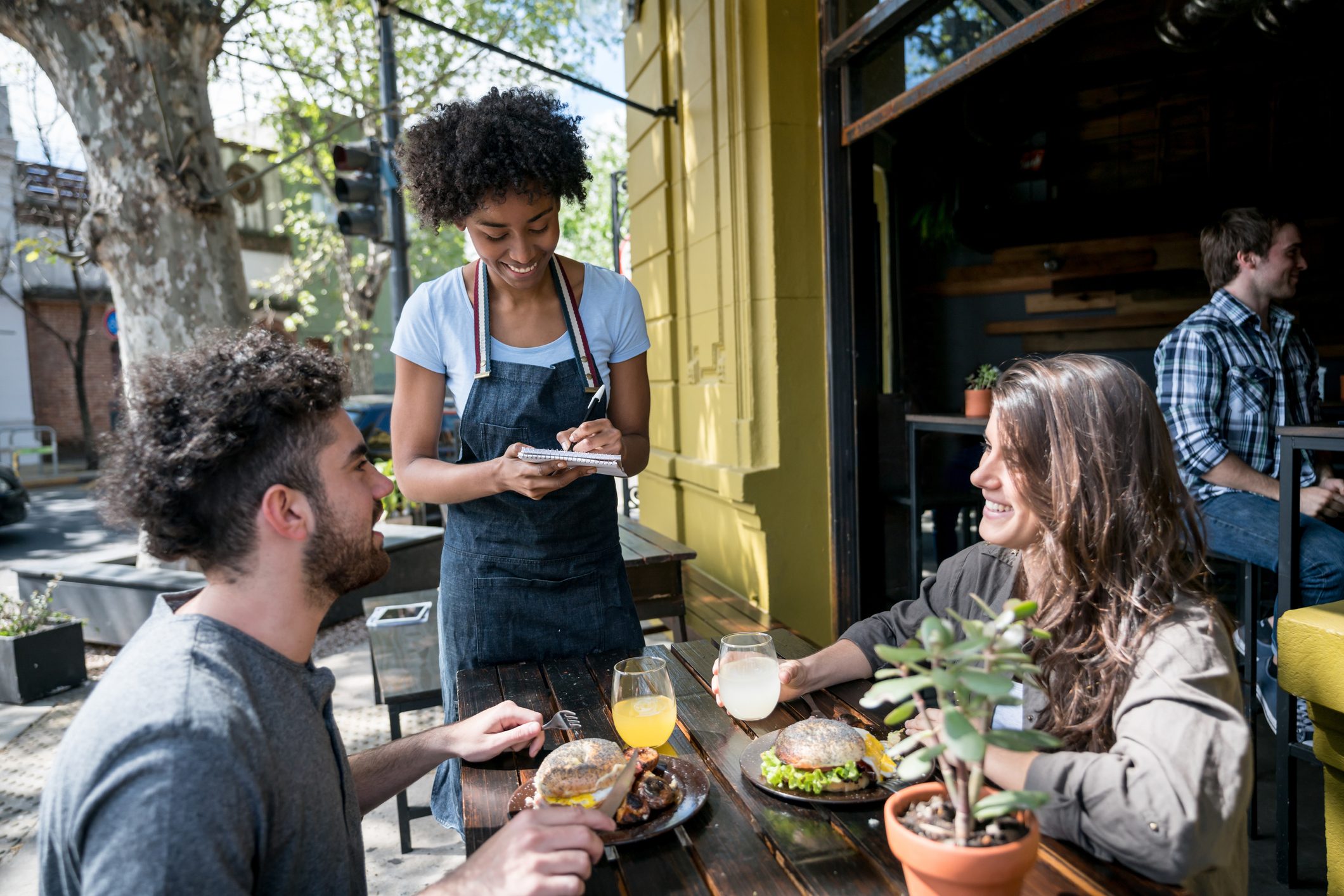 Happy couple enjoying lunch on a lovely day and ordering something to the waitress
