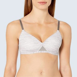 A person wears a light gray bra with slender straps, standing against a plain light background.