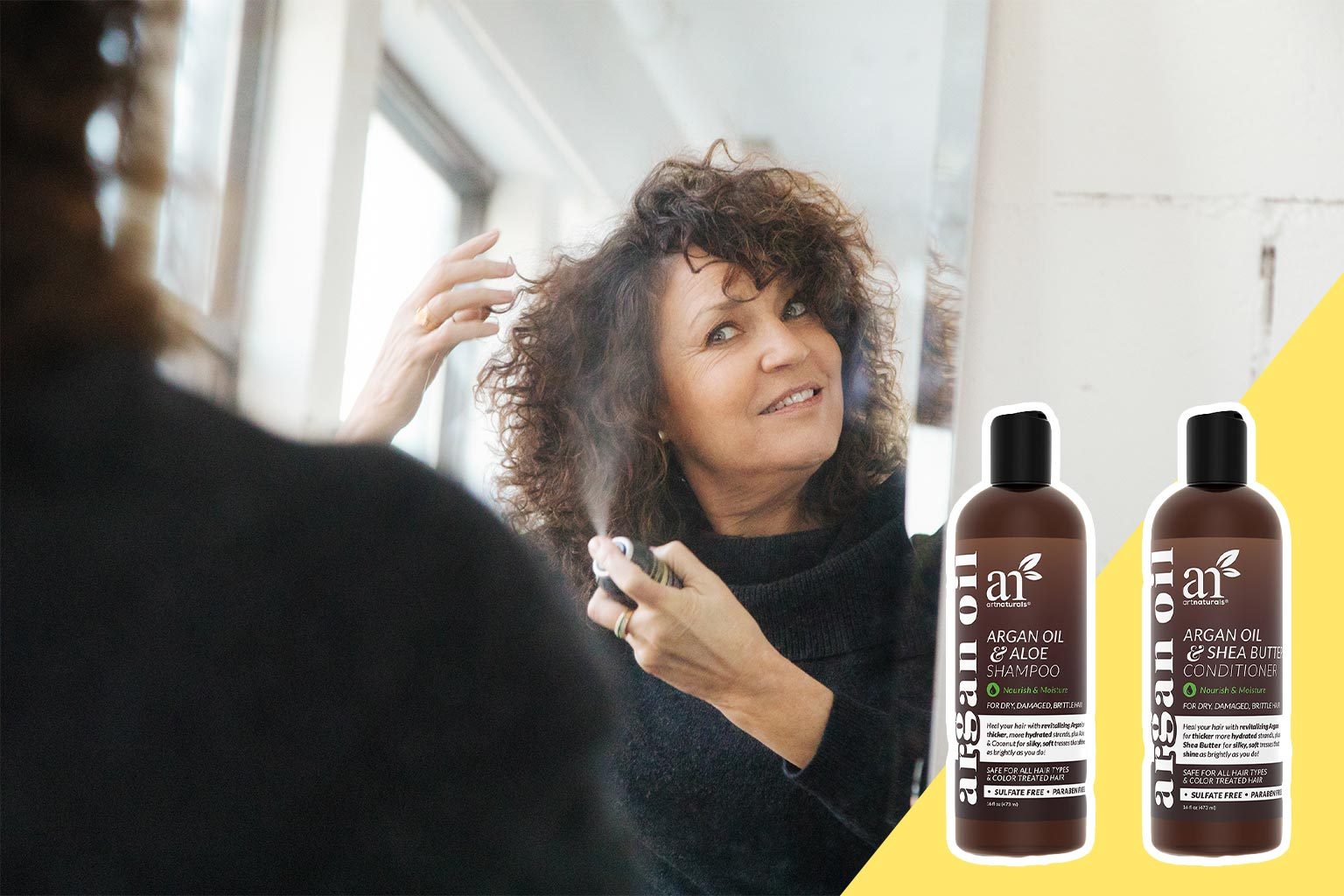 Woman sprays hair while looking in mirror; two shampoo bottles with text "Argan Oil & Aloe Shampoo" and "Argan Oil & Shea Butter Conditioner." Bright room.