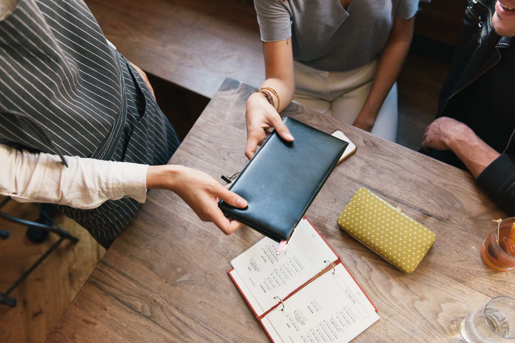 "Restaurant worker handing young couple bill, mid section"