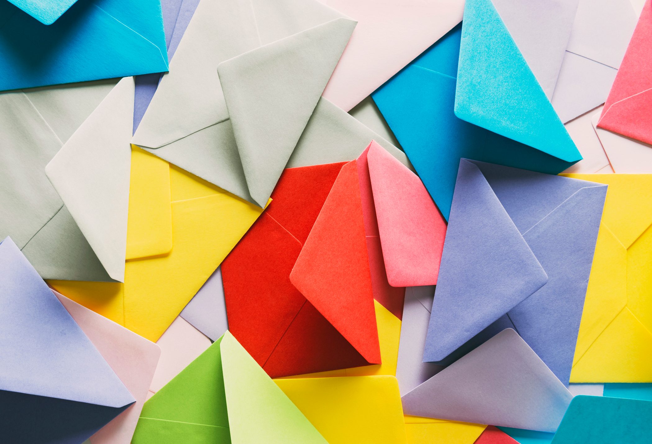 Colorful envelopes scattered overlapping, creating a vibrant and textured collage with various hues including blue, red, yellow, and green.