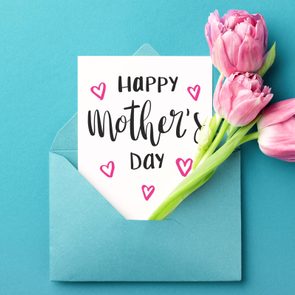 Card rests inside an open blue envelope with pink tulips, on a turquoise background. Text reads 