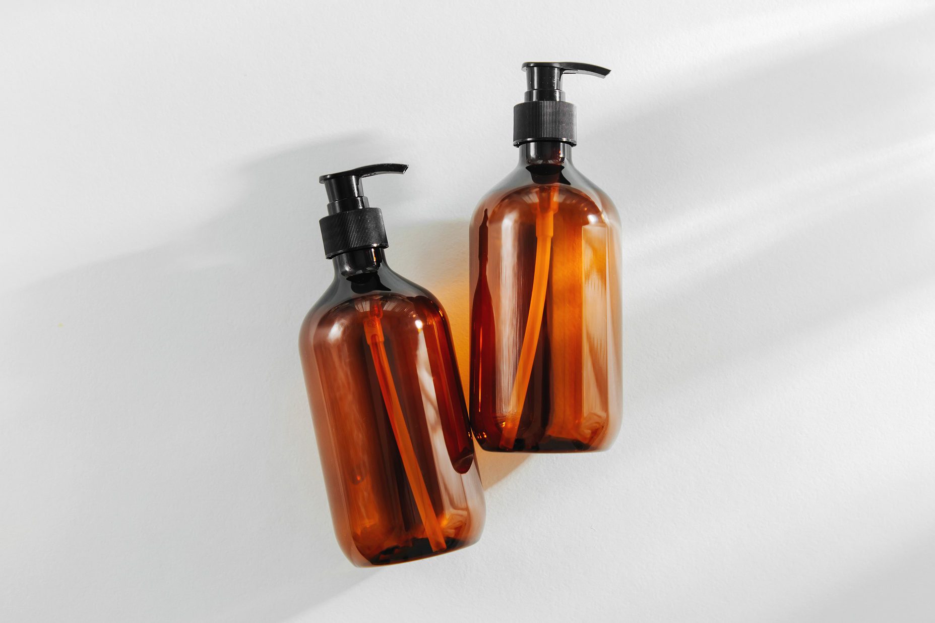 Two brown pump bottles resting on a white surface, casting soft shadows.