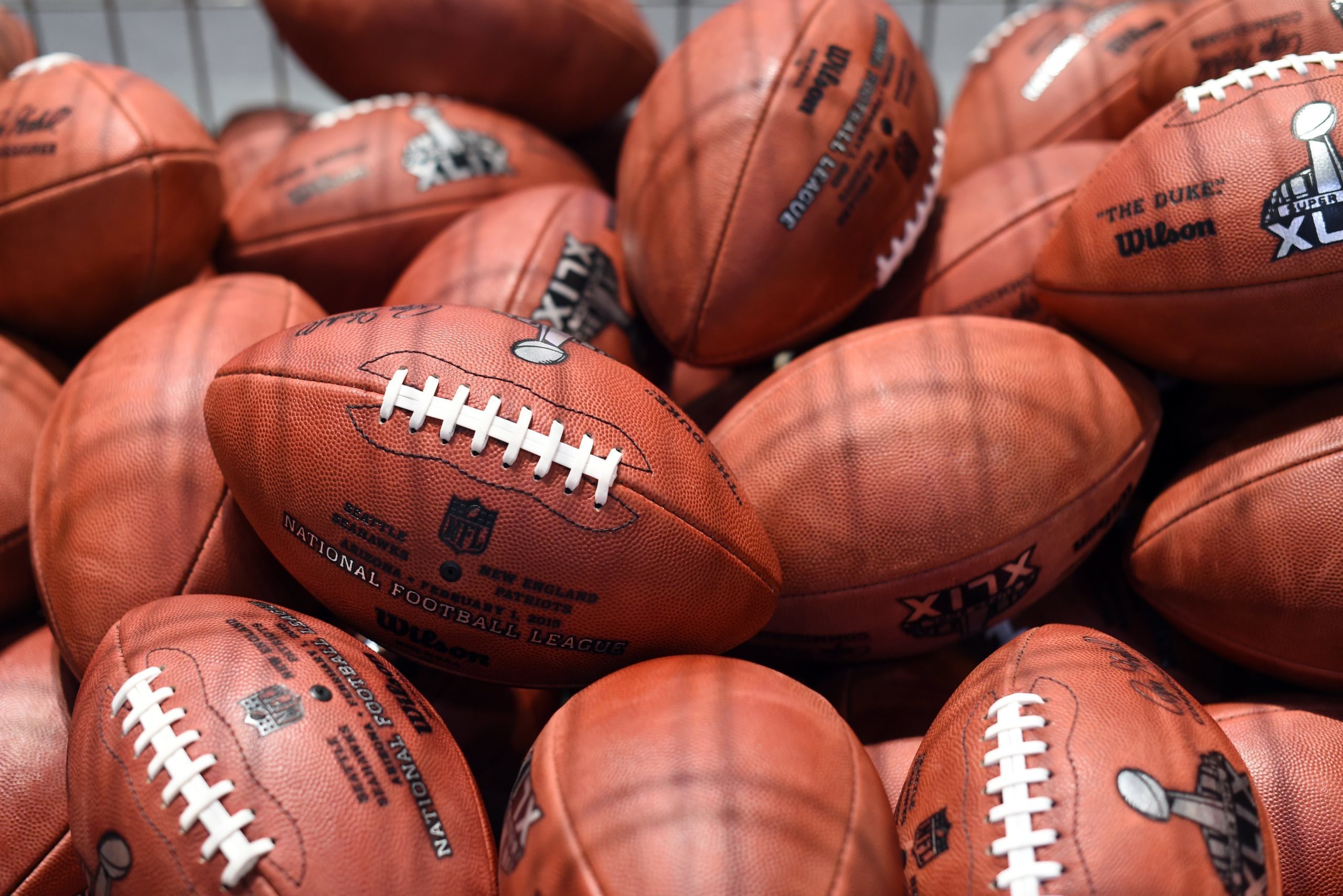 Football pile arranged closely, showcasing logos and text in a sports equipment setting.